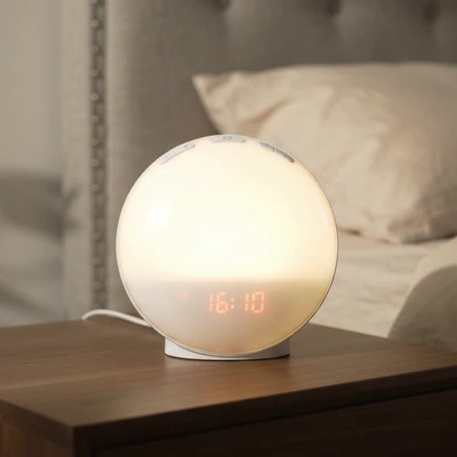 Réveil lumineux Aubéa allumé en lumière blanche chaude sur une table de chevet